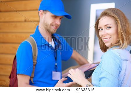 Smiling delivery man in blue uniform delivering parcel box to recipient - courier service concept