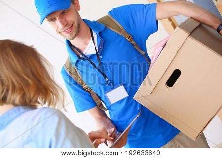 Smiling delivery man in blue uniform delivering parcel box to recipient - courier service concept