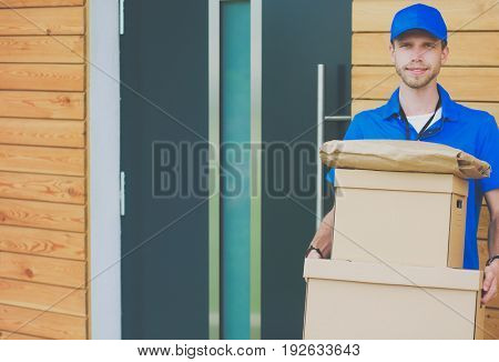 Smiling delivery man in blue uniform delivering parcel box to recipient - courier service concept