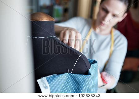 Fashion designer measuring a dress on mannequin.