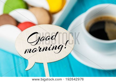 Wooden plaque with wish on background of macaroons and cup of coffee