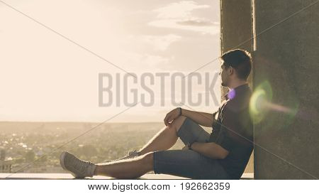 A lonely roofer on the roof of the high-rise at sunset. Courage and adrenaline. Loneliness and calmness