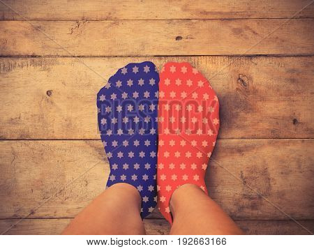 Selfie feet wearing blue and red socks with white star shape on wooden floor background vintage filter effect. American flag and 4th of July concept.