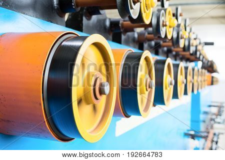 Rotating rubberized wheels of the winding machine. A lot of rotating wheels are yellow.