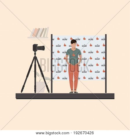Guy vloglogger in a T-shirt, sneakers in front of the camera on a tripod. Behind the back seamless pattern flat