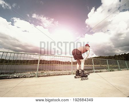 Roller Skater In Action. Man Ride In Inline Skates Ride Along Promenade Handrail, Sky In Background