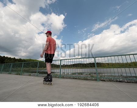 Roller Skater In Action. Man Ride In Inline Skates Ride Along Promenade Handrail, Sky In Background