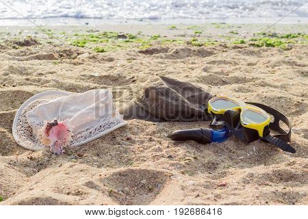 Women's hat for sun protection men's cap and black and yellow diving mask with snorkel on the sandy beach against the sea at morning