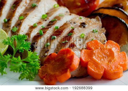 Homemade chicken breast fillet barbecue with grilled vegetables. Close-up concept of chicken breast barbecue.Sliced grilled chicken breast served with vegetable and sprinkle with chopped spring onion. Chicken steak with macro concept.