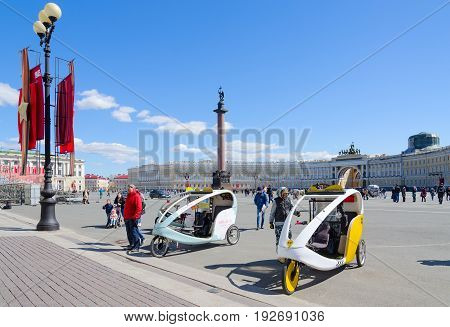 SAINT PETERSBURG RUSSIA - MAY 3 2017: Unknown people walk on Palace Square. Bicycle taxi for walks St. Petersburg Russia