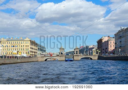 SAINT PETERSBURG RUSSIA - MAY 3 2017: View of Lomonosov Bridge across Fontanka River. Unknown people walk along street St. Petersburg Russia