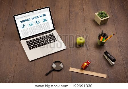 Laptop computer on wooden desk with office suplies