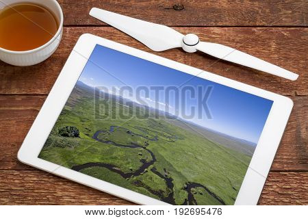 Illinois River meanders through Arapaho National Wildlife Refuge, North Park near Walden, Colorado, reviewing and editing aerial images on a digital tablet