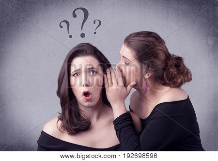 A teenager girl looking confused with drawn question marks above the head, while a girlfriend whispers something in her ear concept.