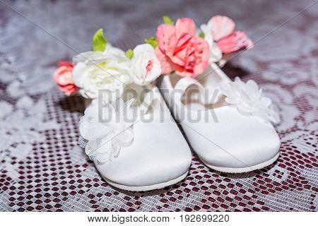 Pair of white baby shoes on pants and shirt at Christening Baptism Ceremony at church