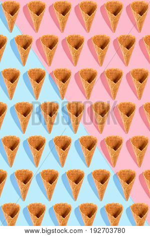 Sugar waffle cone for ice cream arranged in pattern on pink and mint background. The image with copy space can be used as a background for the design of the confectionery menu, cards, greetings, invitations, pattern