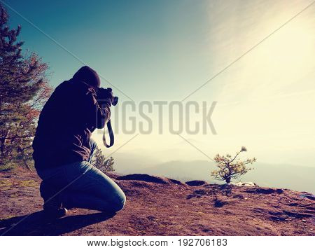 Photographer  Look Down Into Fogy Valley. Man Is Kneeling On Cliff And Takes Photos.
