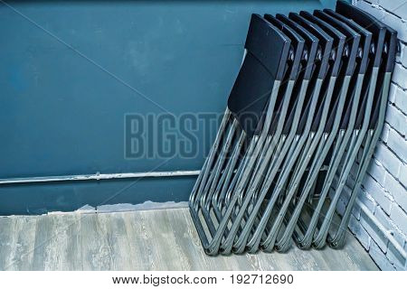 Several black plastic chairs leaned against a wall in office