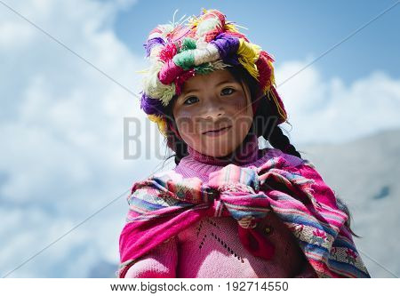 Smiling peruvian girl dressed in colourful traditional handmade outfit. October 21 2012 - Patachancha, Cuzco, Peru