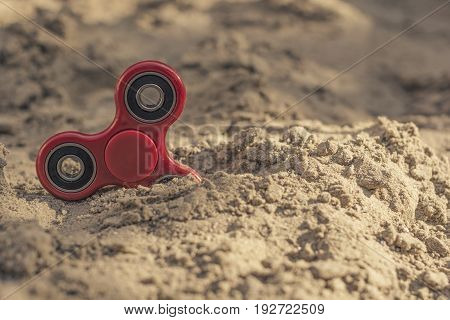 Popular red spinner gadget in 2017 against the background of sand.