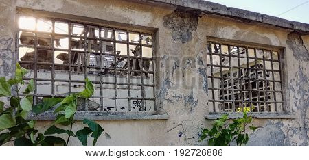 Ruined, abandoned and damaged building with windows and bars on it