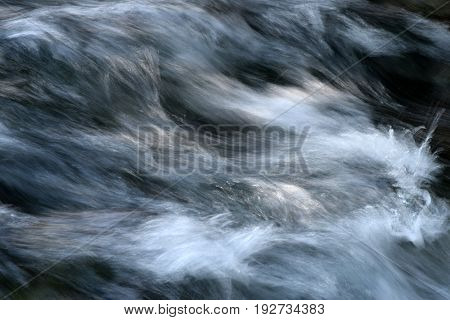 Turbulent water flowing over the rocks in the creek and sparkling