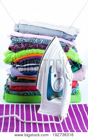 Stack Of Clothing And Iron On A White Background