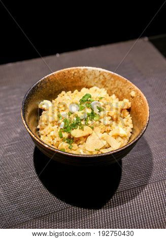 Fried rice with garlic and butter and toping with sliced green onion on traditional cray bowl.
