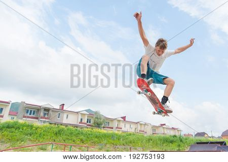Young intense skateboarder in high jump against the sky and sleeping areas
