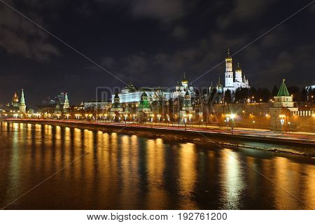Cityscape of Kremlin wall at night with reflection in a river.