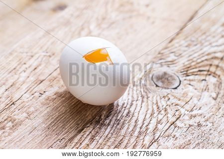 Broken raw egg and yolk on wooden background