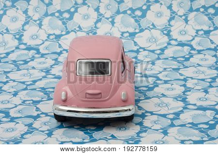 XALAPA, VERACRUZ, MEXICO- APRIL 19, 2017: Pink toy Volkswagen Super Beetle car on a flowers background.
