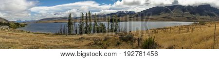 Middle Earth New Zealand - March 14 2017: Panorama shot of Lake Clearwater with dry wasteland in front and the mountains in the back. All under blue cloudy sky.