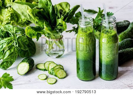 Detox diet. Two small bottles of fresh green smoothies with ingredients on a light wooden background