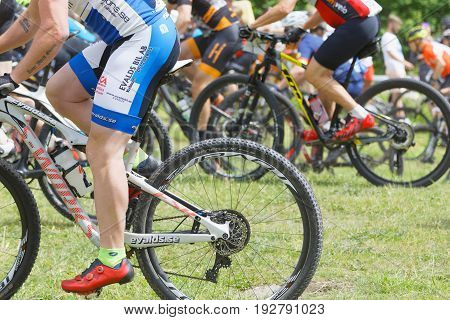 STOCKHOLM SWEDEN - JUNE 11 2017: Side view of legs and feet group of male mountain bike cyclists at Lida Loop Mountain bike Race audience in background. June 11 2017 in Stockholm Sweden