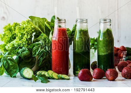 Fresh green smoothies and strawberry smoothie with ingredients on a light wooden background. Healthy detox drinks