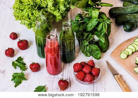 Fresh green smoothies and strawberry smoothie with ingredients on a light wooden background. Healthy detox drinks