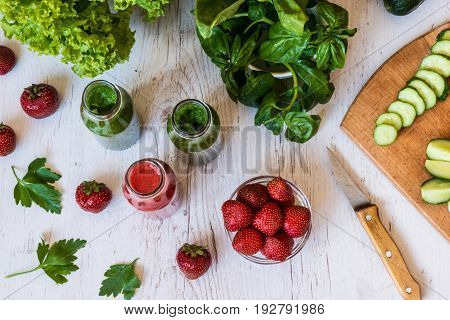 Top view. Fresh green smoothies and strawberry smoothie with ingredients on a light wooden background. Healthy detox drinks