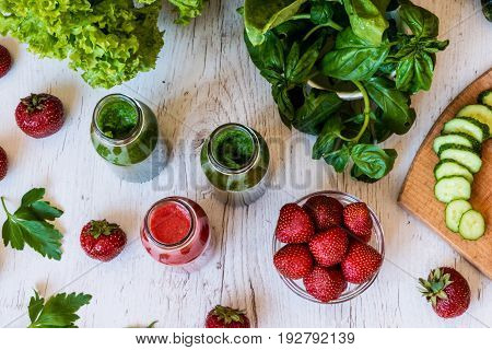Top view. Fresh green smoothies and strawberry smoothie with ingredients on a light wooden background. Healthy detox drinks