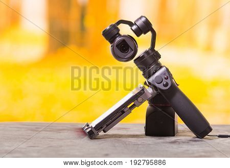 QUITO, ECUADOR- DECEMBER 22, 2017: Osmo Mobile gimbal, new generation of electronic stabilizer over a wooden table in a blurred forest background.