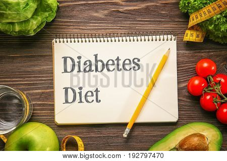 Notebook with text DIABETES DIET and healthy food on wooden background. Health care concept
