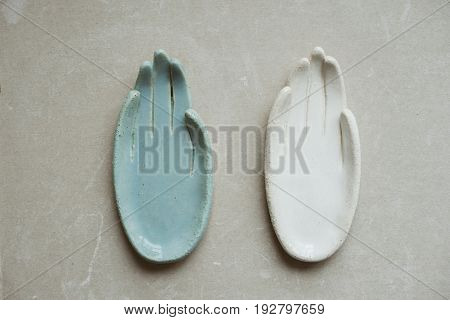 Top view on chamotte clay blue and white hands for holding rings and little things on grey industrial table