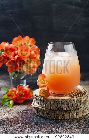 Floral pastel peach and pink brunch cocktail garnished with quince flowers over old rustic background.