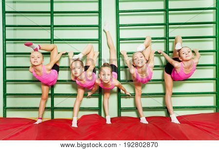 Group of 11-12 years old girls stretching near wall mounted gym ladder during gymnastic class