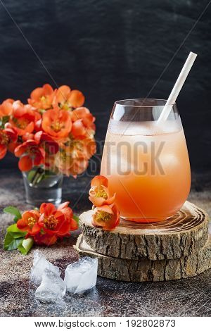 Floral pastel peach and pink brunch cocktail garnished with quince flowers over old rustic background.