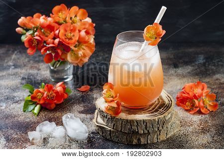 Floral pastel peach and pink brunch cocktail garnished with quince flowers over old rustic background.