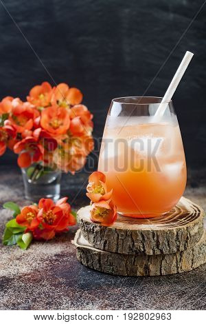 Floral pastel peach and pink brunch cocktail garnished with quince flowers over old rustic background.