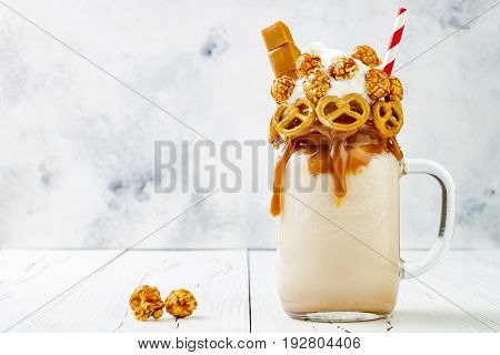 Salted caramel indulgent exreme milkshakes with brezel waffles popcorn and whipped cream. Crazy freakshake food trend. Copy space