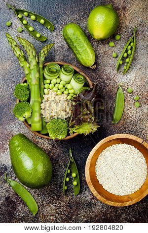 Vegan detox green Buddha bowl recipe with quinoa cucumber broccoli asparagus and sweet peas. Top view flat lay