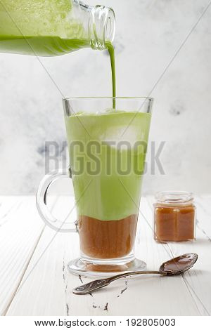 Matcha latte with salted caramel in tall glass.